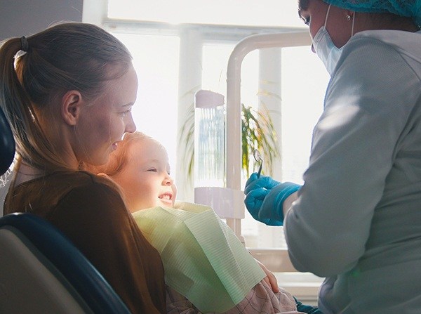 Mother with child in lap during dental treatment