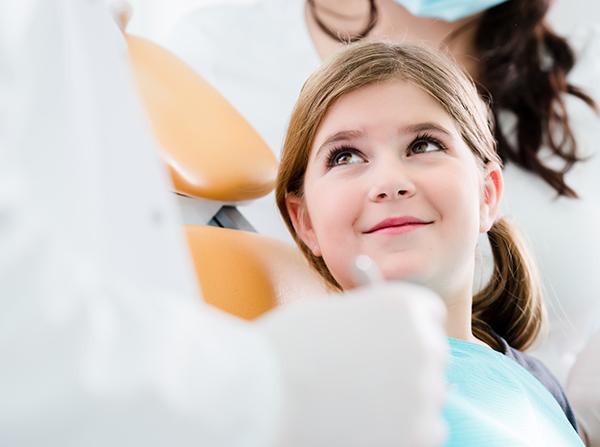 Child in dental chair smiling at dentist