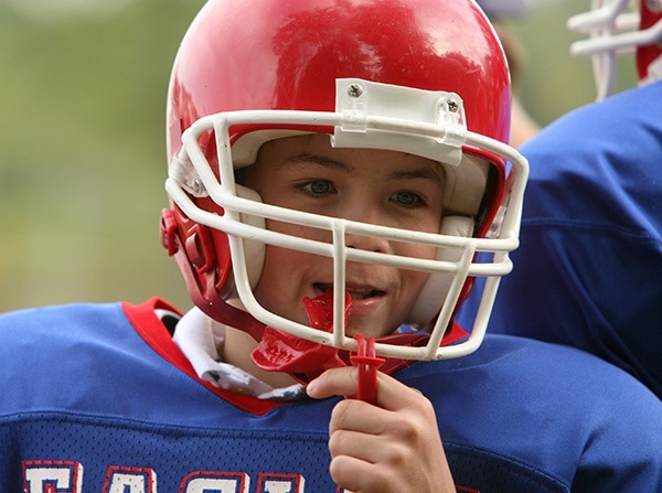 Teen boy in football helmet with red mouthguard