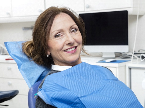 Middle-aged woman with brown hair smiling in dental chair