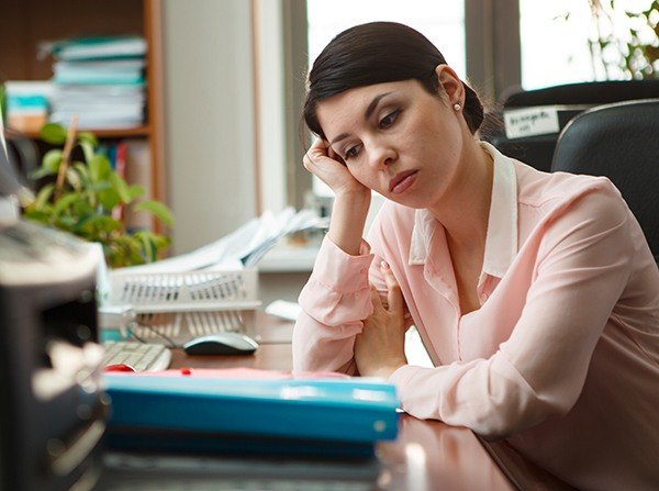Tired woman at desk with head resting on hand