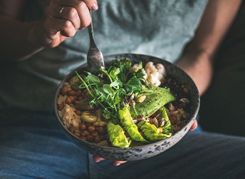 Someone holding salad in bowl over their lap