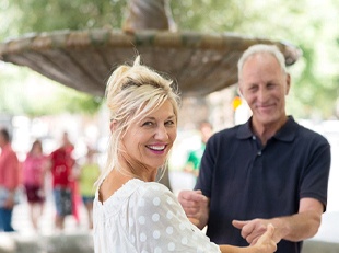 An older couple smiling and dancing together while outside