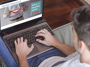 Man on laptop looking at dental insurance