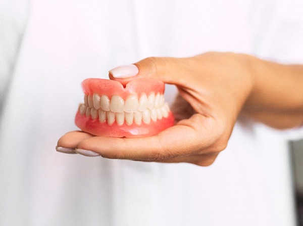 Dentist holding full dentures in Leesburg