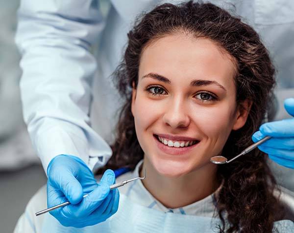 Woman preventing dental emergencies in Leesburg by visiting dentist