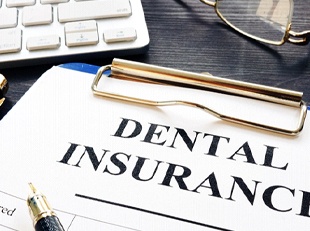 Dental insurance form resting on a table next to keyboard
