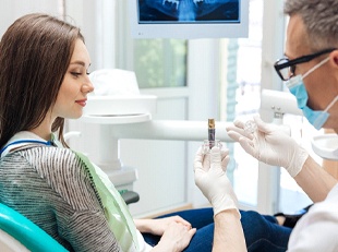 A dentist explains to a female patient how a dental implant works during a consultation