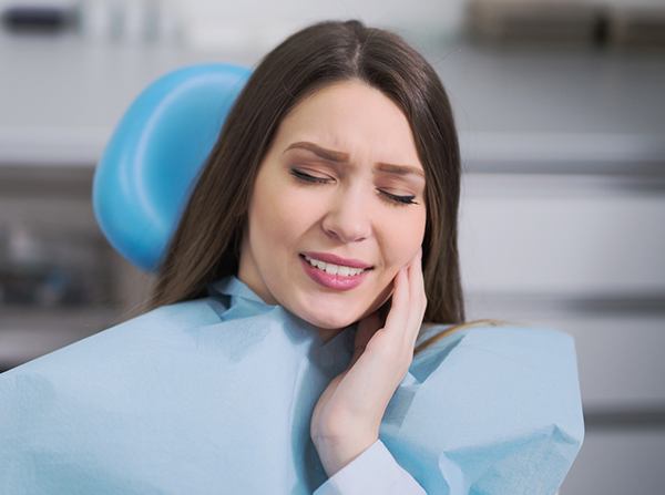 Woman in dental chair holding cheek