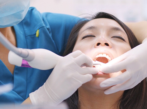 A dental professional performing gum disease treatment on a female patient