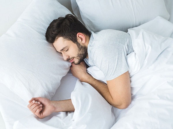 Man in grey shirt sleeping in bed