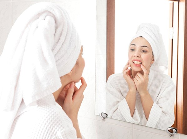 Woman looking at teeth in bathroom mirror