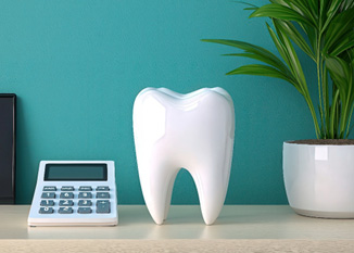 Large model tooth on desk next to large calculator and potted plant