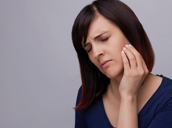 Woman rubbing jaw due to pain from wisdom tooth in Leesburg, VA