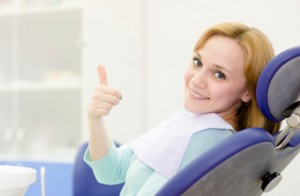 Woman in dentist chair giving thumbs up