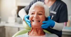 Senior woman in dentist's chair smiling with dentures.