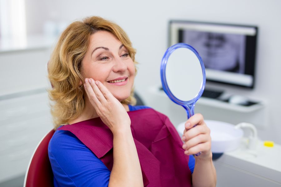A woman looking at her smile in a mirror