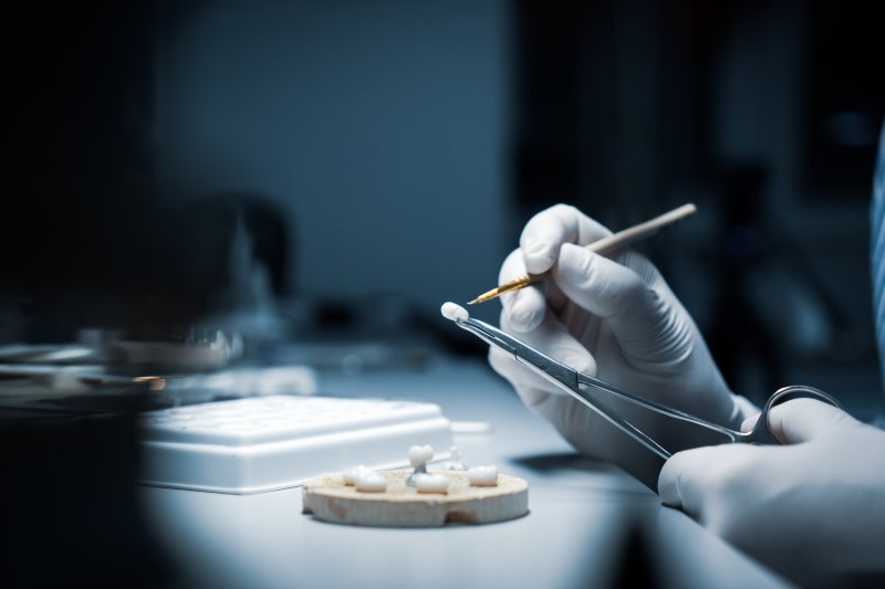 A dentist working on coloring a dental crown