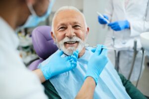 Senior man with dentures in dentist's chair.