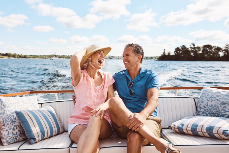 Smiling couple sits in back of boat.