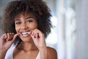 young woman flossing dental implants