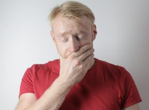 Man with dental pain covering face